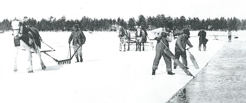 black and white photo of a group of men harvesting ice on a lake using large saws and a horse-drawn plow