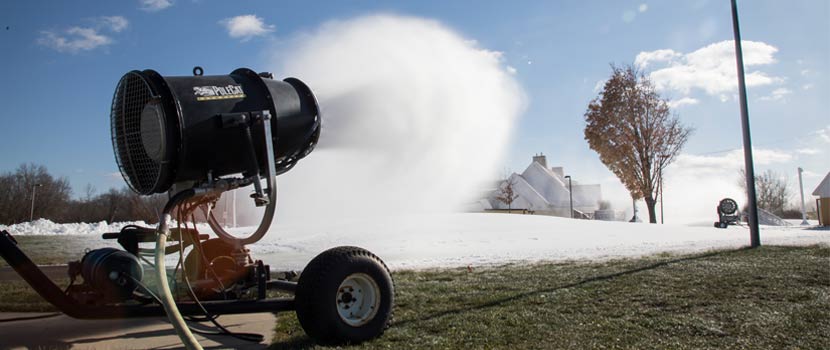 machine making and blowing snow over grassy park
