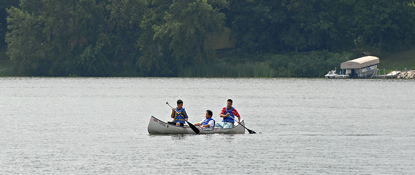 A family canoes across a wide lake