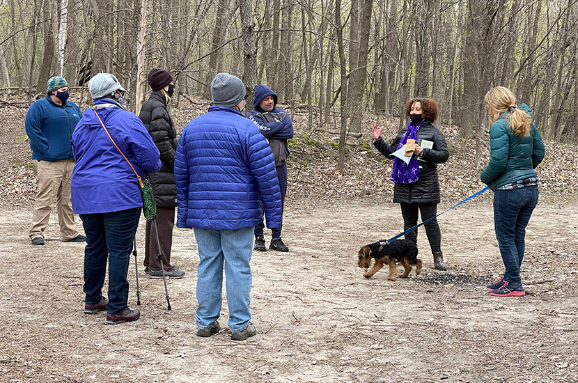 Group of people and one dog on a leash gather on a wooded trail in French Regional Park.
