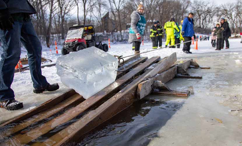 A large block of ice is pulled on a wooden chute out of the lake.