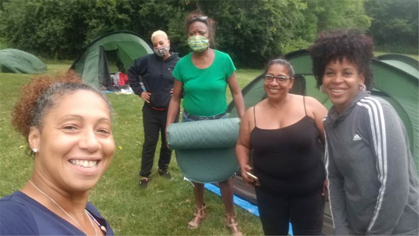 Five women take a selfie outside while camping.