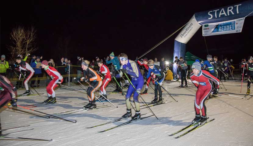 high school cross-country skiers taking off at the start of a race