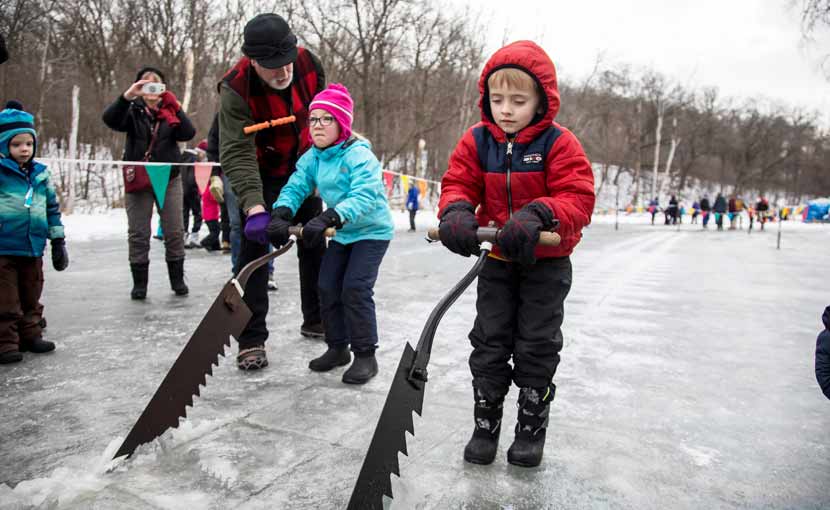 two children using large saws to cut ice