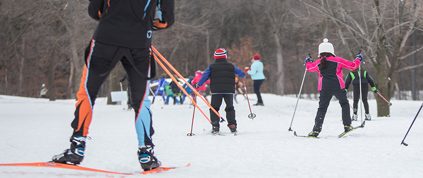 Several kids ski down a cross-country trail