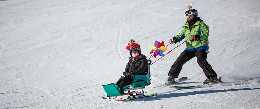 An adaptive skier wears a festive helmet