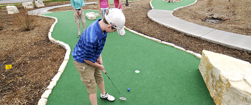 A boy putts on a mini golf course