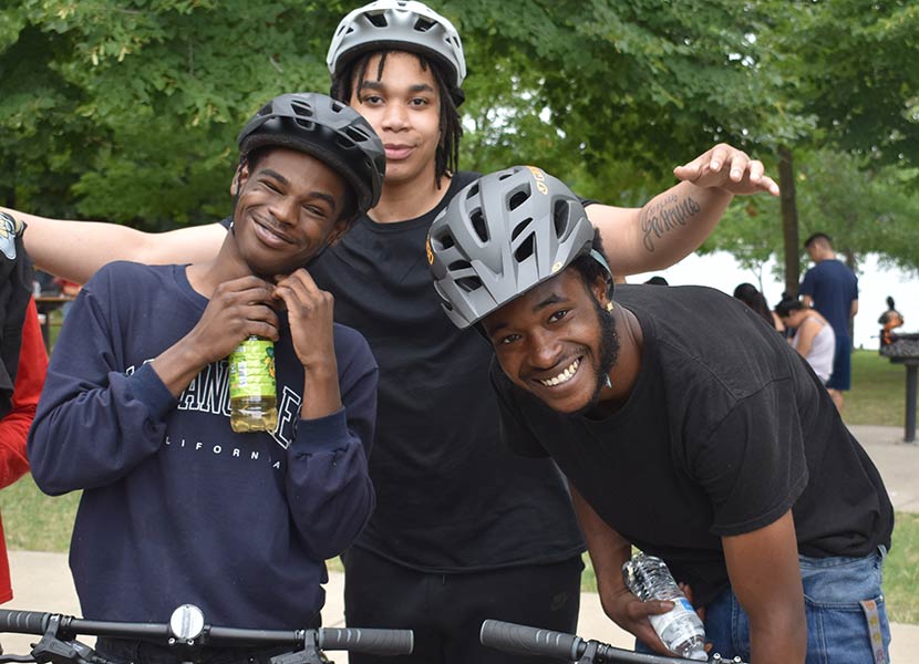 Three boys wear bike helmets and pose for a photo.