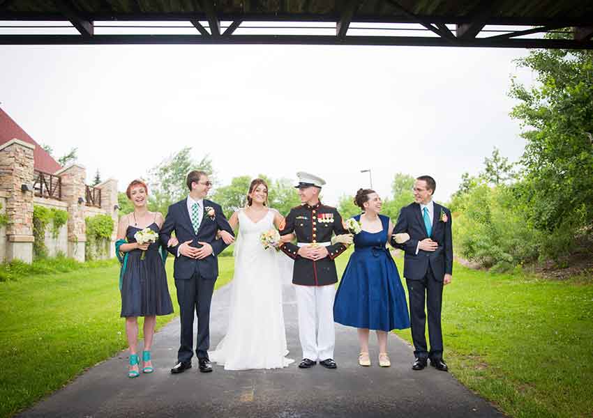 wedding party standing on a trail underneath a walking bridge