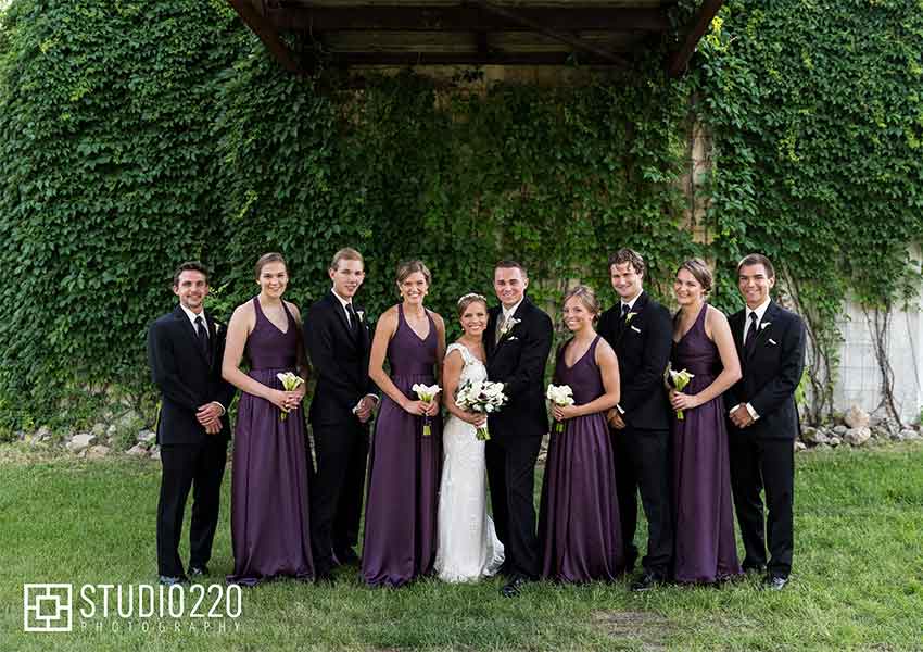 wedding party alongside a wall of leafy green vines