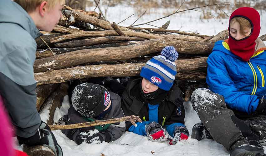 a group of kids building a stick fort in winter