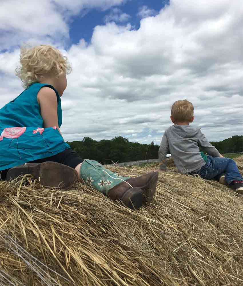 two kids sitting on top of hay bales watching a cloudy sky at Gale Woods Farm in Minnetrista