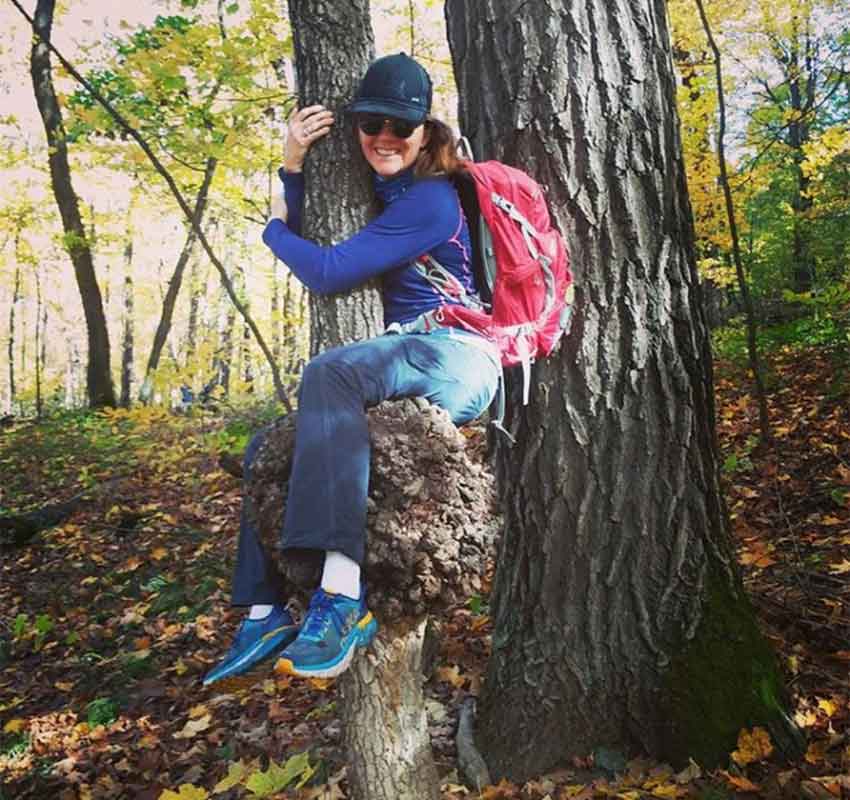 A woman hugs a tree.