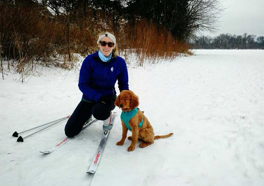 Jessica on skis with her puppy Jasper next to her