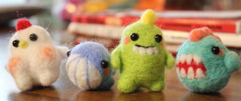 A photo of four creatures made of of felted wool.